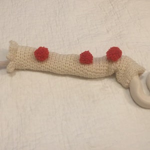 May include: A white crocheted snake sweater with three red pom-poms.