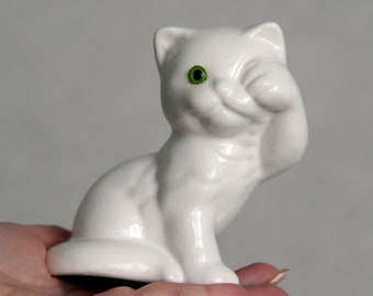 Vintage White kitten figure. Ceramic cat. Washing face. Green glass eye. White glazed cat.