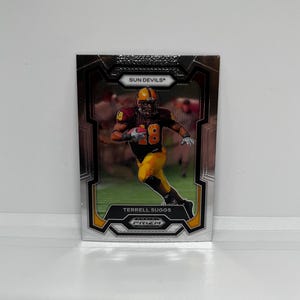 May include: A silver and black football trading card featuring Terrell Suggs, a player for the Arizona State Sun Devils. The card has a gold border and the text "PRIMZM" is visible in the bottom right corner.