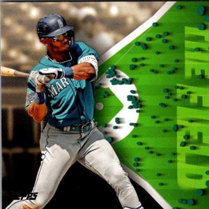 May include: A baseball card featuring Julio Rodríguez of the Seattle Mariners. The card has a green background with the words "Roving the Field" in a 3D style. The player is wearing a blue and white baseball uniform and is holding a bat.