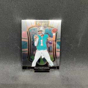 May include: A football trading card featuring Tua Tagovailoa of the Miami Dolphins. The card has a silver and teal design with the player in his uniform, throwing a football. The card is from the Select 2022 series.