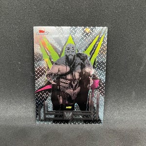 May include: A trading card featuring a wrestler with a long beard and fur accents. The card has a silver background with a diamond pattern and green and pink accents. The word "WAR" is printed on the card.
