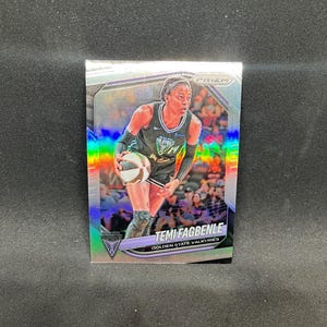 Könnte beinhalten: Eine silberne Prizm-Sport-Sammelkarte mit Temi Fagbenle von den Golden State Valkyries. Die Karte hat ein holografisches Finish, zeigt eine Basketballspielerin im schwarzen Trikot mit Ball und den Text Temi Fagbenle Golden State Valkyries.