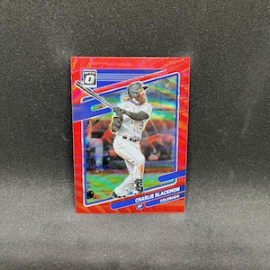 May include: A red Optic baseball card featuring Charlie Blackmon of the Colorado Rockies. The card has a red and blue design with a player in action. The Optic logo is visible in the upper left corner.