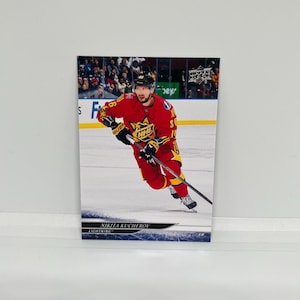May include: A hockey trading card featuring Nikita Kucherov in a red and yellow uniform. The card shows Kucherov skating on the ice with a hockey stick. The text "NIKITA KUCHEROV LIGHTNING" is at the bottom of the card.