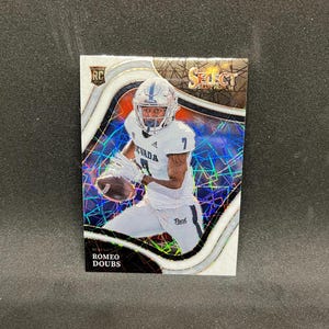 May include: A football trading card featuring Romeo Doubs in a white Nevada uniform. The card has a holographic background with the words "Select Draft Picks '22" and "RC" visible. The player is holding a football.