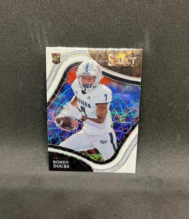 May include: A football trading card featuring Romeo Doubs in a white Nevada uniform. The card has a holographic background with the words "Select Draft Picks '22" and "RC" visible. The player is holding a football.