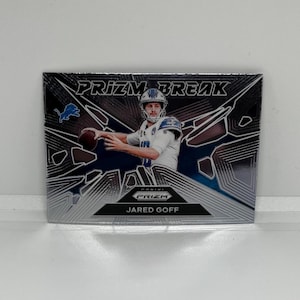 May include: A silver and black football trading card featuring a football player in a blue and white uniform throwing a football. The card has the text "PRIZM BREAK" and "JARED GOFF" on it.