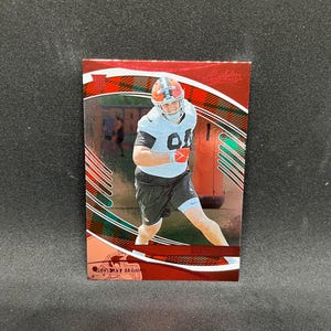 May include: A red and brown football trading card featuring a player in a white and brown uniform. The card has a plaid design and the words "Absolute Football" at the top. The player is wearing a helmet and shorts.