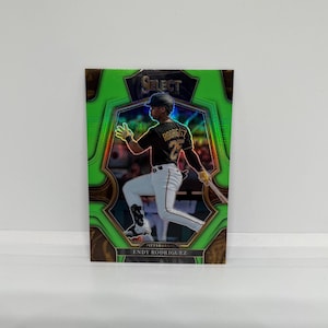 以下が含まれることがあります： 緑と金の野球カード。黒と金のユニフォームを着た野球選手が写っており、カードには「SELECT」と「ENDY RODRIGUEZ」の文字が書かれている。