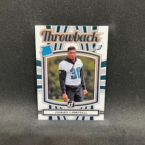 Könnte beinhalten: Eine Football-Sammelkarte mit Jihadd Campbell im Eagles-Trikot. Die Karte hat einen weißen Rand mit grünen und grauen Streifen und das Wort "Throwback" oben. Die Karte trägt auch die Worte "Rated Rookie" und das Donruss-Logo.