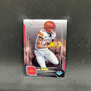 May include: A Chase Sowell Iowa State football trading card. The card features a player in a red helmet and white uniform holding a football. The card has a silver border and the word "Chrome".