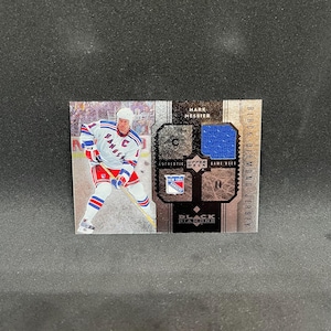 May include: A rectangular Upper Deck Black Diamond sports trading card featuring Mark Messier in a New York Rangers uniform. The card includes a blue fabric jersey swatch, the text Mark Messier, Black Diamond Jersey, and a team logo emblem.