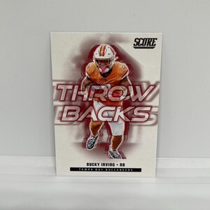 May include: A football trading card featuring Bucky Irving of the Tampa Bay Buccaneers. The card has the word "THROWBACKS" in large letters. The Score logo is in the upper right corner.