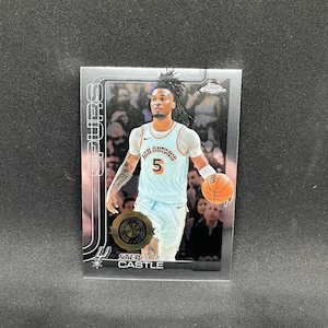 May include: A basketball trading card featuring Stephon Castle of the San Antonio Spurs. The card has a silver border and a photo of the player in his team uniform, holding a basketball. The card also includes the NBA logo and the words "Chrome" and "Spurs".