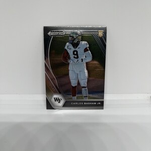 May include: A silver and black football trading card featuring a football player wearing a white jersey with the number 9. The card has a silver background with a black border and the text "PRIZM" and "RC" in the top right corner. The card also has the text "WF" and "CARLOS BASHAM JR." in the bottom left and right corners.