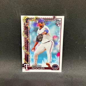 May include: A baseball trading card featuring Kumar Rocker of the Texas Rangers in a pitching pose. The card has a festive border with snowflakes and the text "Rangers" and "Kumar Rocker". The Topps RC logo is visible.