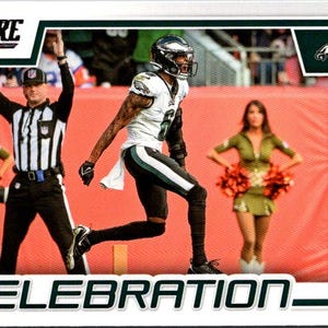 Puede incluir: Un jugador de fútbol americano con un uniforme verde y blanco celebra un touchdown con un árbitro y animadoras de fondo. La imagen es de una tarjeta de intercambio Score e incluye el nombre del jugador, "DeVonta Smith", y la palabra "CELEBRATION".