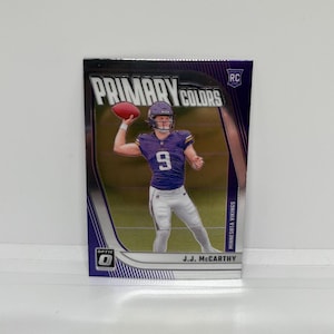 JJ McCarthy #20 Minnesota Vikings; Novato - Inserto de colores primarios; Balón de fútbol Panini Donruss Optic 2024