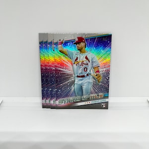 May include: A baseball card featuring a baseball player wearing a red and white uniform with the text "St. Louis" on the front. The card has a rainbow background with the text "Stars of MLB" and "Marvin Winn" on the bottom.