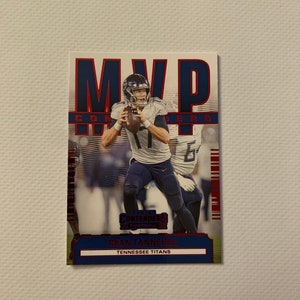 May include: A red, white, and blue football card featuring Ryan Tannehill, quarterback for the Tennessee Titans. The card is from the Panini Contenders Optic Collection and features the word "MVP" in red and blue.