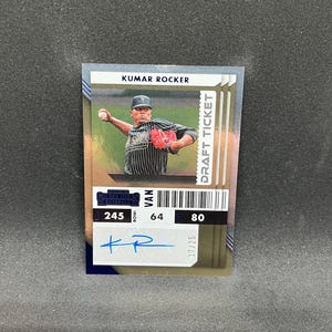 May include: A baseball card featuring Kumar Rocker in a pitching pose. The card has a "Draft Ticket" design with a barcode and the text "Contenders Baseball." It includes an autograph and is numbered 17/25.