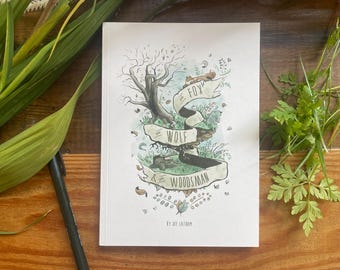May include: A hardcover book with a nature-themed illustration. The cover features a tree, fox, wolf, and the text "Fox, Wolf & Woodsman" on a banner. The book is on a wooden surface with greenery and a pen.