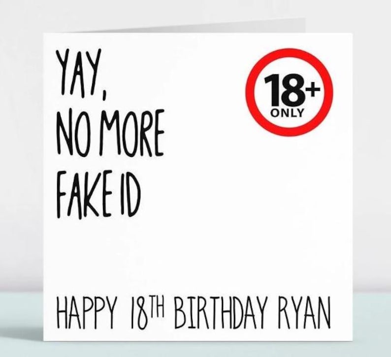 May include: A white card with black text that reads "Yay, No More Fake ID" and "Happy 18th Birthday Ryan". A red circle with a black 18+ Only sign is in the top right corner.