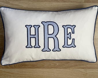 Fodera per cuscino monogrammata, in cotone bianco a righe, con lettere blu navy applicate e bordino.