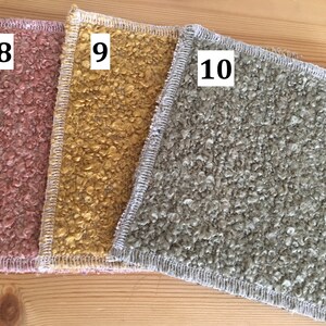 May include: Three textured, square fabric pieces in shades of pink, gold, and gray. Each piece has a white stitched border and a number in the corner: 8, 9, and 10. The fabrics are displayed on a light wood surface.