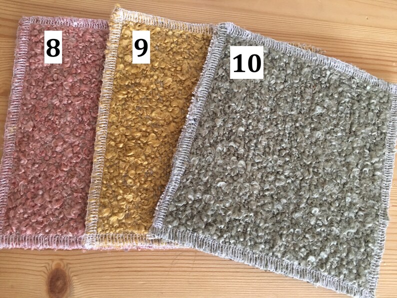 May include: Three textured, square fabric pieces in shades of pink, gold, and gray. Each piece has a white stitched border and a number in the corner: 8, 9, and 10. The fabrics are displayed on a light wood surface.