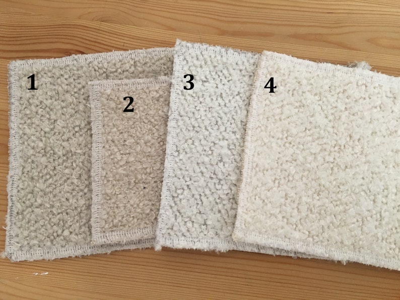 May include: Four rectangular, textured cloths in varying shades of off-white and beige are arranged on a wooden surface. The cloths have a looped, plush texture and are numbered 1 through 4.