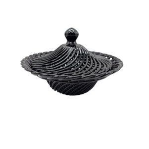 May include: A black decorative bowl with a lid. The bowl is made of a woven material and has a spiral design. The lid has a small knob on top.