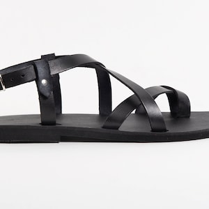 May include: Black leather sandals with a criss-cross strap design and a buckle closure.