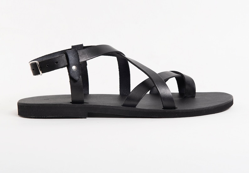 May include: Black leather sandals with a criss-cross strap design and a buckle closure.