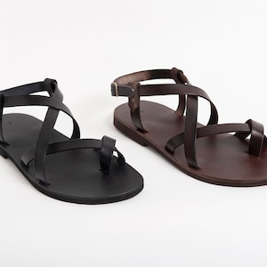 Pu&ograve; includere: Due paia di sandali in pelle con cinturini incrociati. Un paio &egrave; nero e l'altro &egrave; marrone.