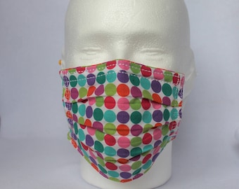 May include: A white face mask with a colorful polka dot pattern. The mask has multiple layers of fabric and is pleated for a comfortable fit.