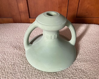 May include: A light green ceramic vase with two handles and a decorative design around the neck.