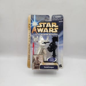 以下が含まれることがあります： スターウォーズのスノートルーパーのアクションフィギュア、オリジナルのパッケージ入り。フィギュアは白で、黒い発射大砲と赤いライトセーバーが付属しています。パッケージにはスターウォーズのロゴと「The Empire Strikes Back」の文字が記載されています。