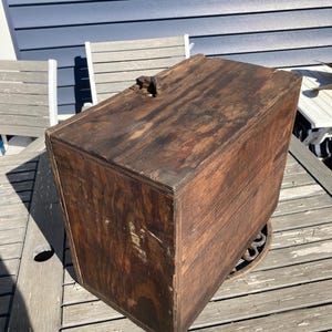 May include: A vintage wooden box with a hinged lid and a metal latch. The box is made of dark wood and has a worn, rustic appearance.