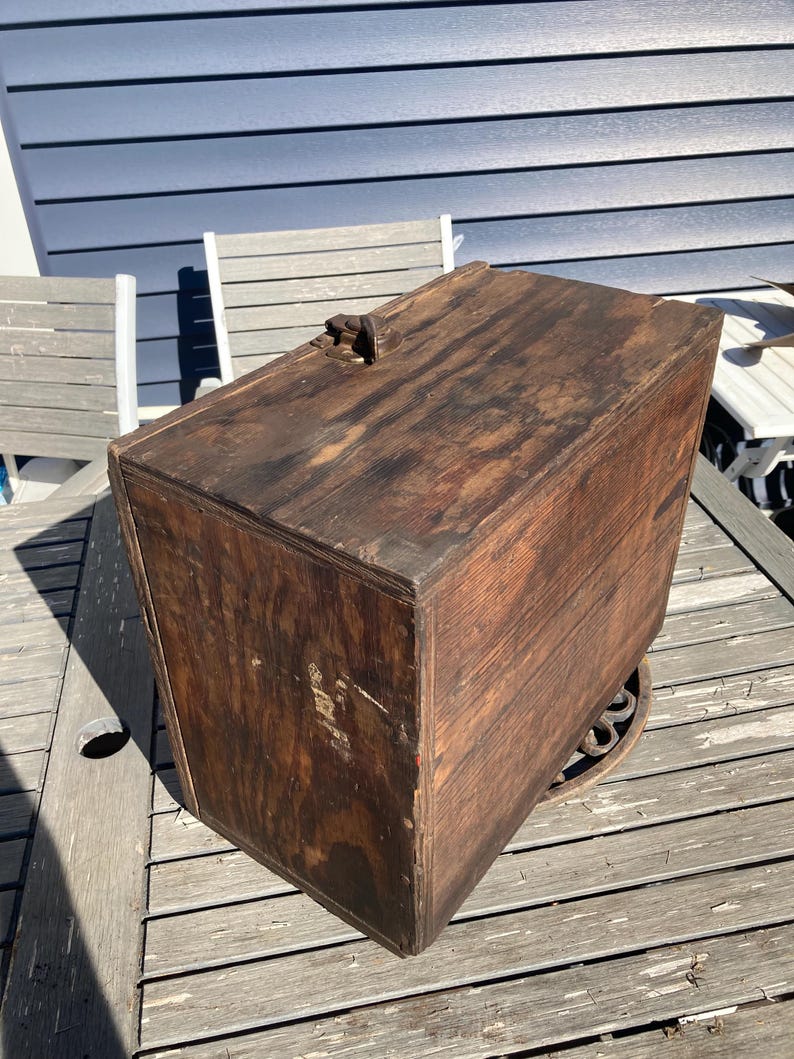 May include: A vintage wooden box with a hinged lid and a metal latch. The box is made of dark wood and has a worn, rustic appearance.