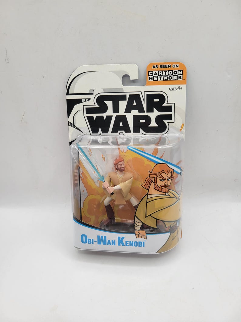 May include: Obi-Wan Kenobi action figure from Star Wars, in a Cartoon Network package. The figure is in a dynamic pose with a lightsaber, set against a fiery background. The packaging features the Star Wars logo and the text "As Seen On Cartoon Network."
