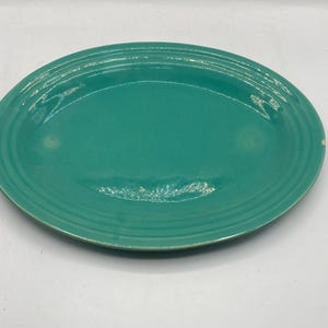 Peut inclure: Un plat de service ovale turquoise avec des détails concentriques en relief sur le bord. Le plat en céramique a une finition brillante et est posé sur un fond blanc. Cette pièce vintage est adaptée pour servir des aliments.