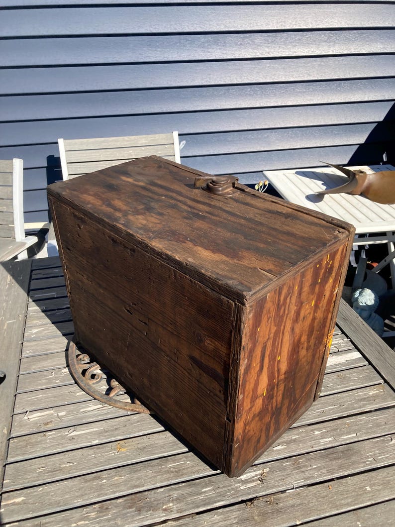 May include: A vintage wooden box with a hinged lid and a metal latch. The box is made of dark wood with a natural finish and has a worn, rustic look.