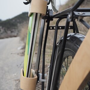 May include: A wooden ski rack attached to a black bicycle rack. The rack is designed to hold two pairs of skis. The rack is made of wood and metal.
