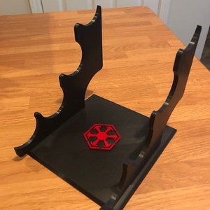 May include: Black plastic stand with four slots for holding lightsabers. The stand has a red Imperial symbol on the base.