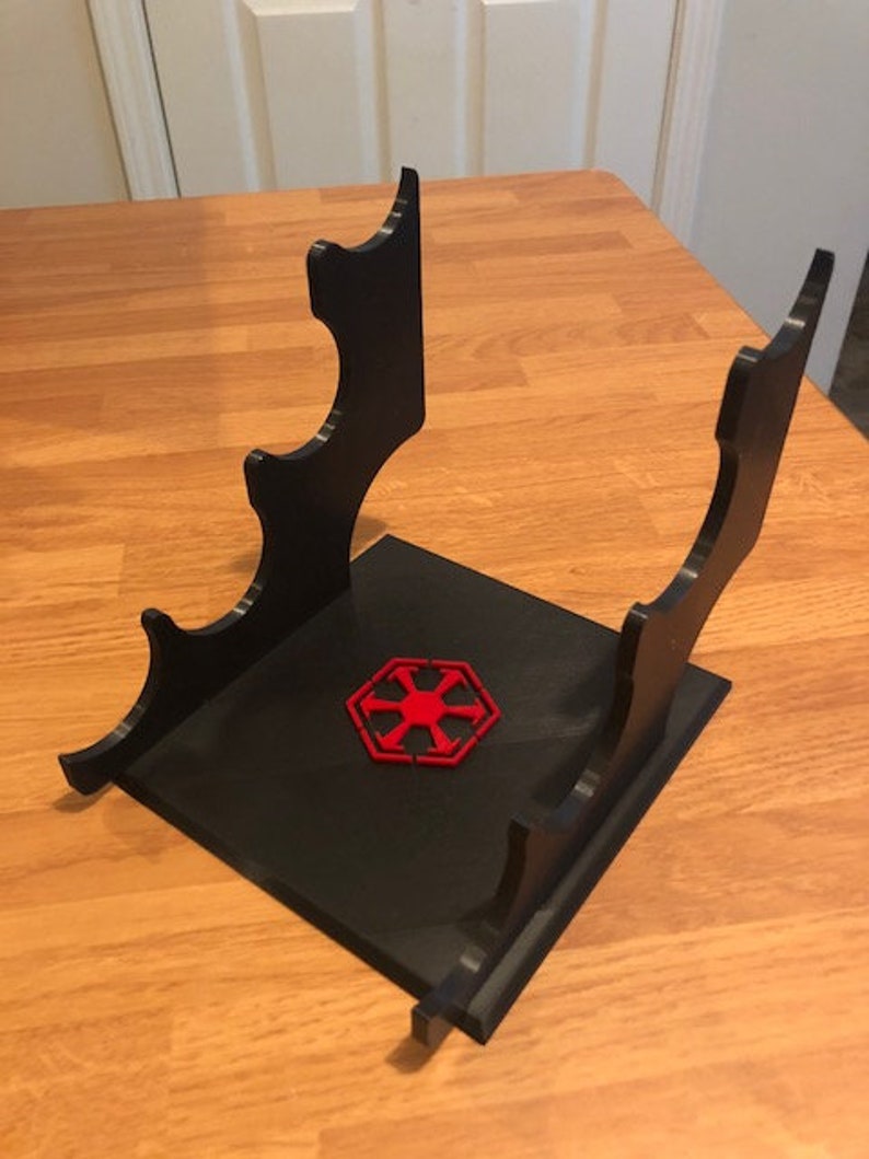 May include: Black plastic stand with four slots for holding lightsabers. The stand has a red Imperial symbol on the base.