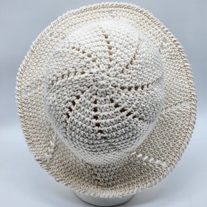 May include: A crocheted sun hat in a cream color with a wide brim and a textured design.