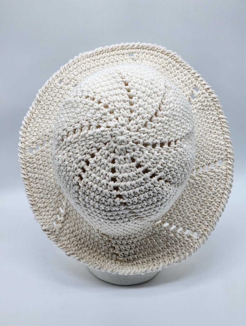 May include: A crocheted sun hat in a cream color with a wide brim and a textured design.