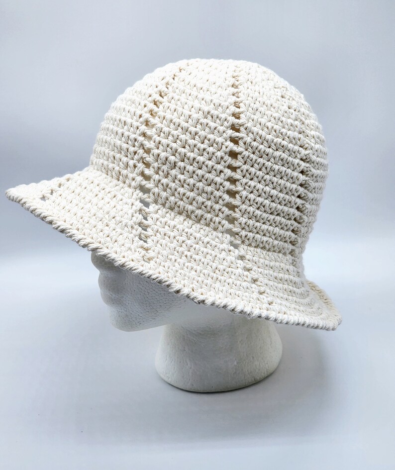 May include: A white crocheted sun hat with a wide brim. The hat is made with a simple stitch pattern and has a slightly slouchy fit.